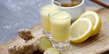 ricette con lo zenzero: vassoio di legno con due bicchieri pieni e radice di zenzero fresco
