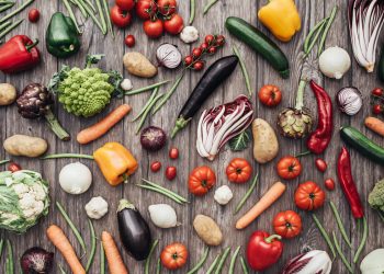 diverse verdure sparse su un tavolo che simboleggiano la dieta vegana