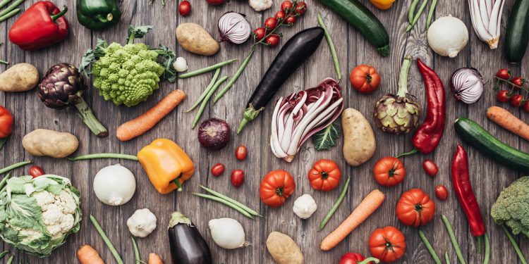 diverse verdure sparse su un tavolo che simboleggiano la dieta vegana