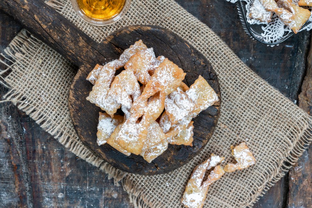 Frappe al forno di Carnevale: ricetta sana e golosa 2 panno di iuta e sopra un vassoio di legno con manico pieno di chiacchiere al forno