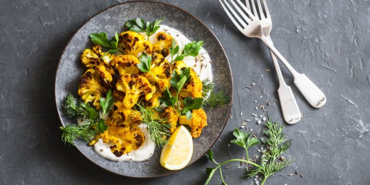 ricette con cavolfiore: piatto tondo grigio con delle cime di cavolfiore saltate