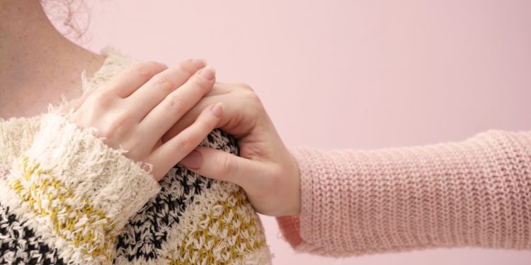 Una donna che mette la mano sulla spalla di un'altra donna in segno di conforto