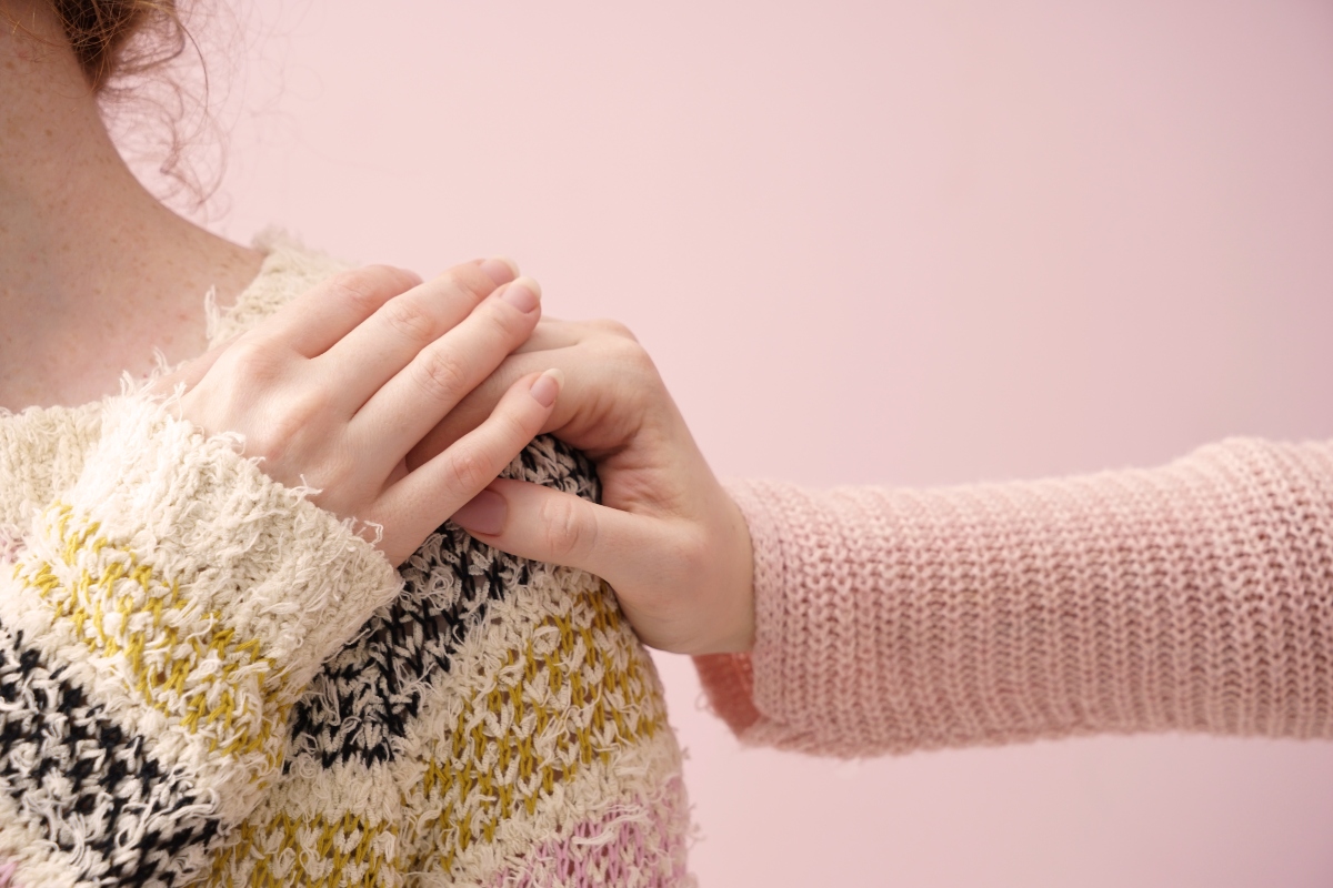 Una donna che mette la mano sulla spalla di un'altra donna in segno di conforto