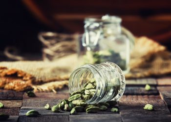 Su un tavolo un contenitore in vetro con alcuni semi di cardamomo