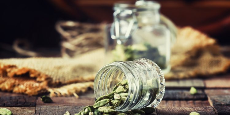 Su un tavolo un contenitore in vetro con alcuni semi di cardamomo