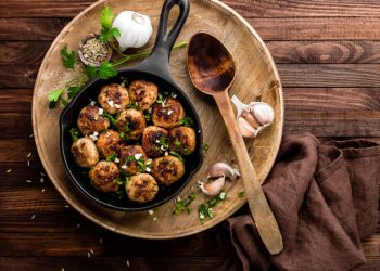 su tavolo di legno, piatto di legno con polpette di melanzane, aglio e un cucchiaio di legno