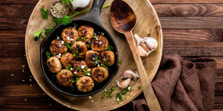 su tavolo di legno, piatto di legno con polpette di melanzane, aglio e un cucchiaio di legno