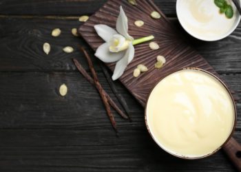un fiore di vaniglia, un baccello di vaniglia e della polvere di vaniglia su un tavolo
