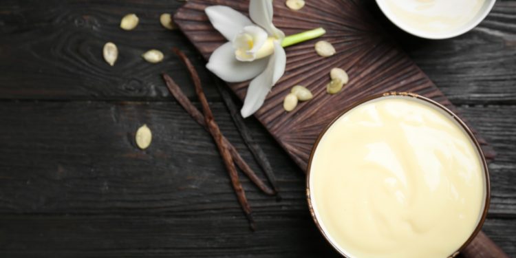 un fiore di vaniglia, un baccello di vaniglia e della polvere di vaniglia su un tavolo