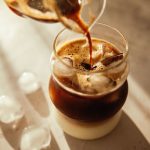 Caffè freddo: la ricetta facile e rinfrescante 1 Caffè freddo versato in un bicchiere con cubetti di ghiaccio e uno strato di latte sul fondo.