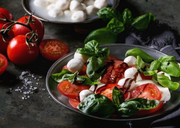 piatto scuro con la caprese, nodini di mozzarella, pomodori e basilico