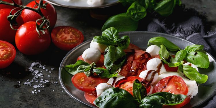 piatto scuro con la caprese, nodini di mozzarella, pomodori e basilico