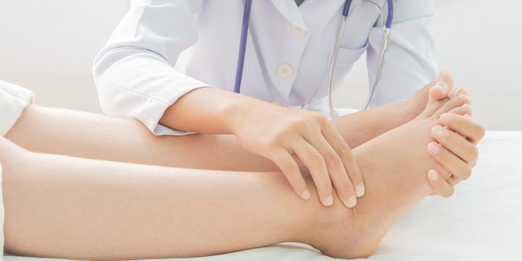 una massaggiatrice massaggia le caviglie di una donna per combattere la ritenzione idrica alle gambe