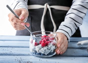 una donna che mescola una macedonia di frutta con semi di chia