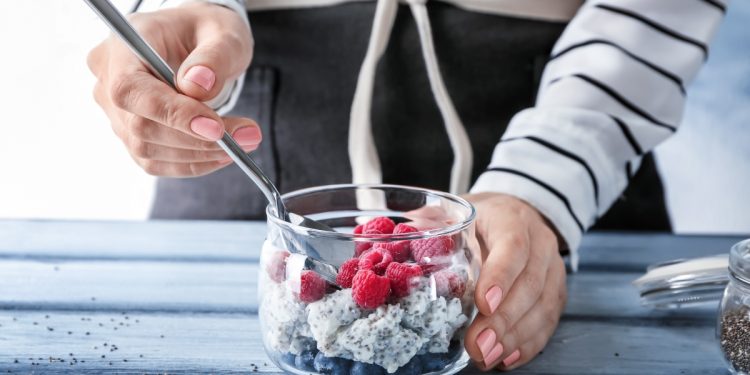 una donna che mescola una macedonia di frutta con semi di chia