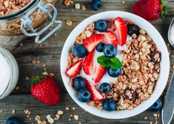 Healthy breakfast granola with fresh strawberry and blueberry on wooden background