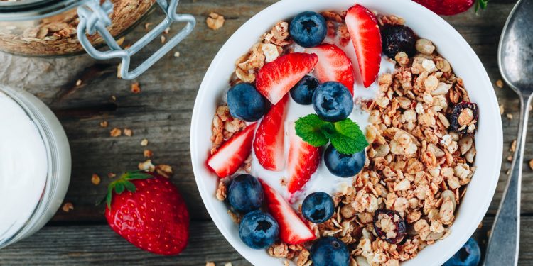 Healthy breakfast granola with fresh strawberry and blueberry on wooden background
