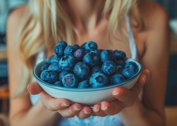 una donna che tiene in mano una ciotola di mirtilli perché hanno poche calorie