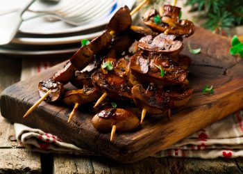 vassoio di legno con spiedini di funghi arrosto
