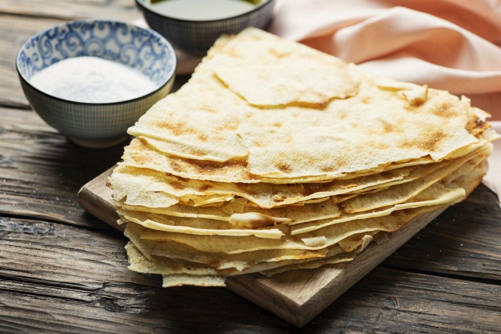 Pane carasau: il pane sardo croccante, ideale per ricette veloci e leggere 4 su tavolo di legno alcune fette di pane carasau una sull'altra
