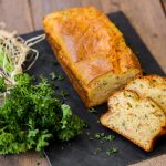 su tavolo di legno, tagliere nero con plumcake salato al salmone e un mazzo di prezzemolo