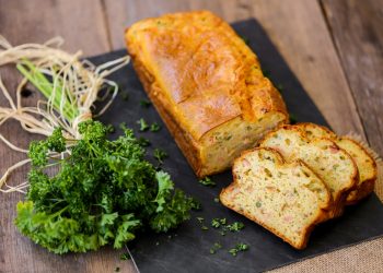 su tavolo di legno, tagliere nero con plumcake salato al salmone e un mazzo di prezzemolo