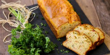su tavolo di legno, tagliere nero con plumcake salato al salmone e un mazzo di prezzemolo