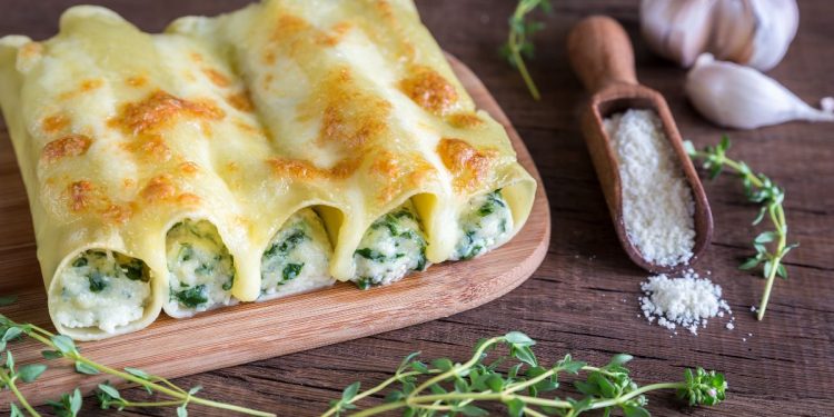 base di legno con sopra cannelloni di ricotta e spinaci, aglio a spicchi
