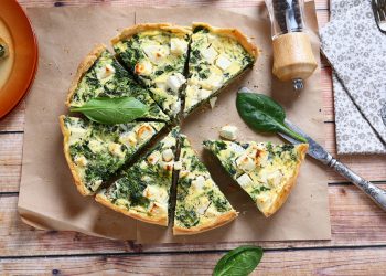 torte salate: su piano di legno una torta salata con verdura tagliata a spicchi