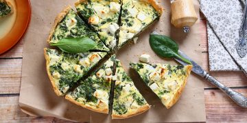 torte salate: su piano di legno una torta salata con verdura tagliata a spicchi