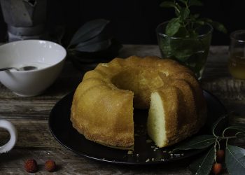 su tavolo di legno piatto nero con una torta 7 vasetti con yogurt, tavolo pronto per colazione con tazza di caffè, erbe aromatiche