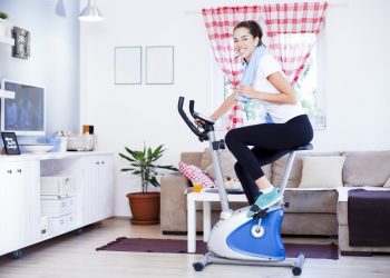 una donna nel salotto di casa sua che si allena con la cyclette