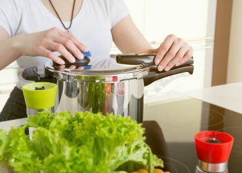 Pentole a pressione: una donna che apre una pentola a pressione per cucinare