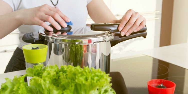 Pentole a pressione: una donna che apre una pentola a pressione per cucinare