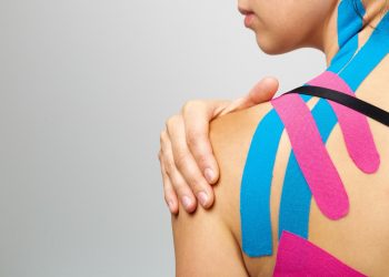 una donna rivolta di spalle che si tocca la spalla colpita da tendinite