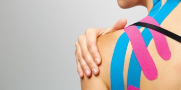 una donna rivolta di spalle che si tocca la spalla colpita da tendinite