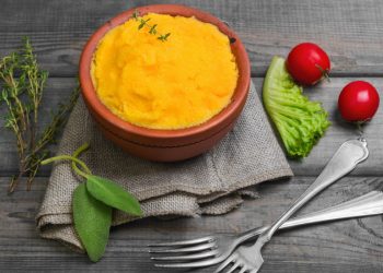su base di legno ciotola di coccio con polenta con carote e verza