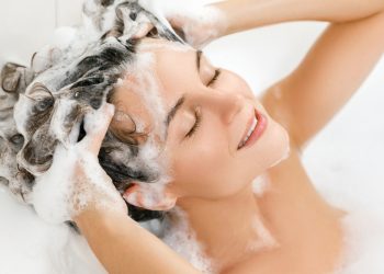 donna in vasca da bagno che si lava i capelli con uno shampoo all'acido ialuronico