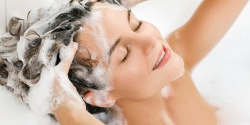 donna in vasca da bagno che si lava i capelli con uno shampoo all'acido ialuronico