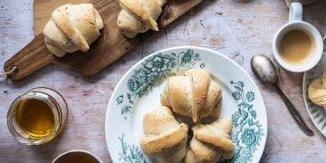 un piatto con tre cornetti e un tagliere di legno con due cornetti