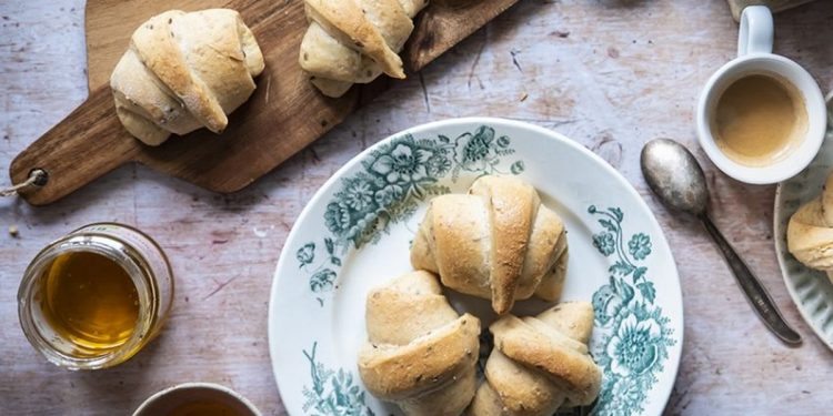 un piatto con tre cornetti e un tagliere di legno con due cornetti