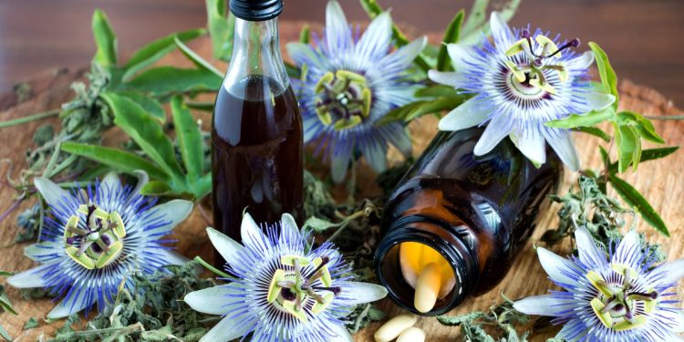 Alcuni fiori di passiflora e due boccette contenenti gocce a base di passiflora