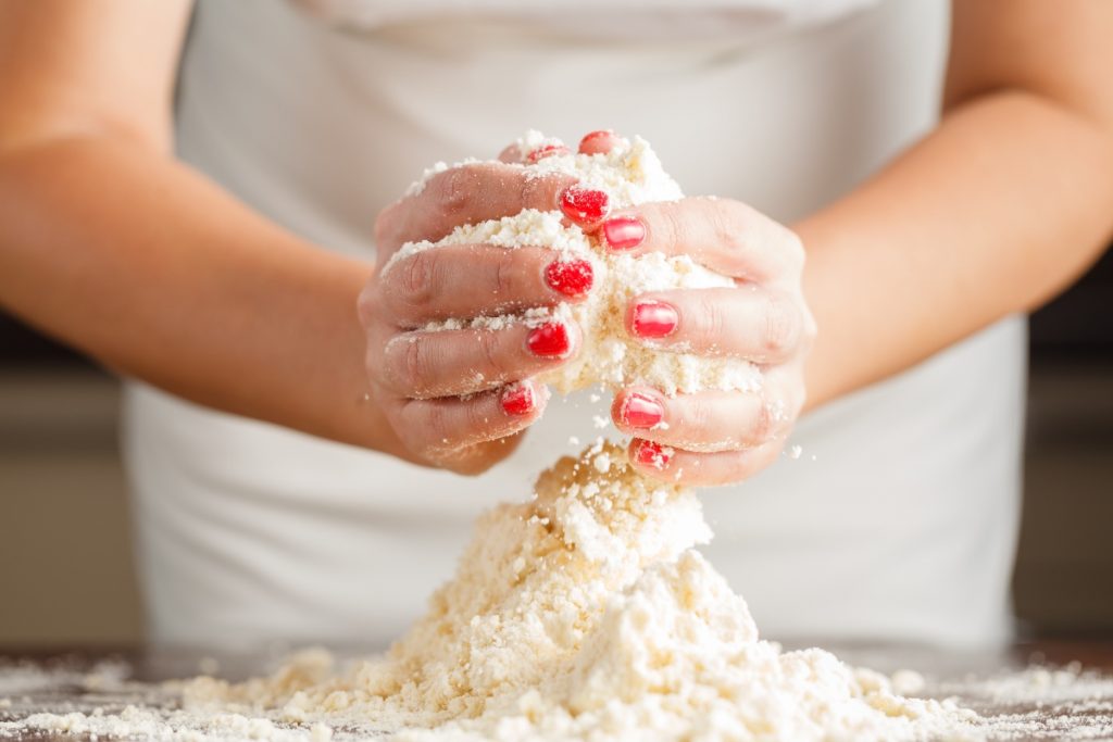 Pasta brisè (brisée): la ricetta base per le tue torte salate 3 le mani di una donna mostrano come lavorare la farina per la pasta brisée per preparare le tue torte salate
