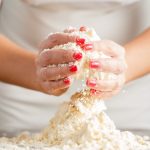 le mani di una donna mostrano come lavorare la farina per la pasta brisée per preparare le tue torte salate