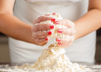 le mani di una donna mostrano come lavorare la farina per la pasta brisée per preparare le tue torte salate