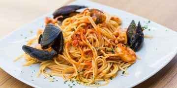 piatto bianco quadrato con porzione di spaghetti allo scoglio