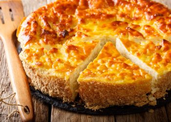 su base di legno primo piano di una torta di riso con uno spicchio tagliato, mestolo di legno