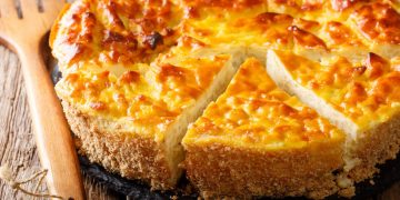 su base di legno primo piano di una torta di riso con uno spicchio tagliato, mestolo di legno