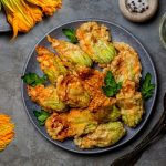 su tavolo da cucina di ardesia, piatto nero con fiori di zucca fritti e attorno fiori di zucca