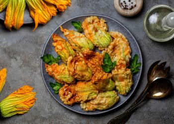 su tavolo da cucina di ardesia, piatto nero con fiori di zucca fritti e attorno fiori di zucca